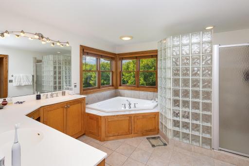 This private, generously sized en suite bathroom is an elegant retreat featuring dual sinks, a soothing jacuzzi tub, and a walk-in shower. This space blends everyday practicality with spa-like serenity and ample storage.