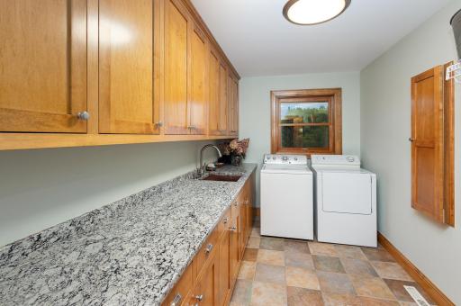 Conveniently located off the mudroom, the main floor laundry room is both efficient and elegant, featuring custom maple cabinetry, a sleek undermount sink, and durable granite countertops.