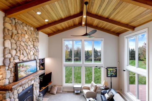 From the staircase landing, take in a breathtaking view of the soaring two-story family room, where the warmth of a natural wood ceiling meets walls of windows that frame the pristine backyard beyond.