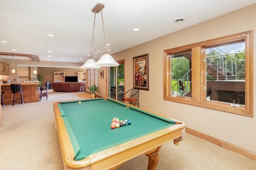 From the pool table area, enjoy a clear view toward the stylish bar and kitchenette. Beyond, a walk-out sliding door leads to the expansive patio, creating a natural extension of the indoor space and connecting effortlessly to outdoor living.