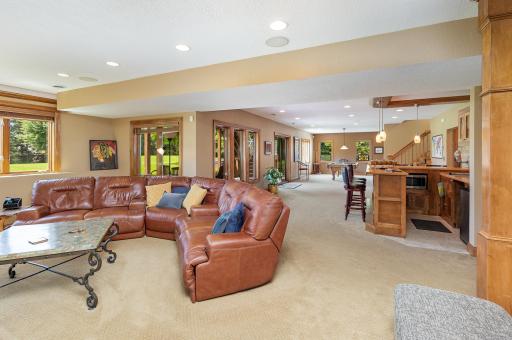 The oversized walkout great room offers clear sightlines to the stylish bar, billiards area, and the expansive patio beyond. Natural flow and open views make this an ideal hub for entertaining, relaxing, or seamless indoor-outdoor living.