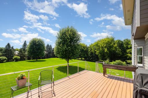 Off the kitchen, step onto a beautiful composite deck. Framed by a sleek Clearview railing system, the space offers unobstructed views of the manicured backyard, where privacy and natural beauty create a serene retreat.