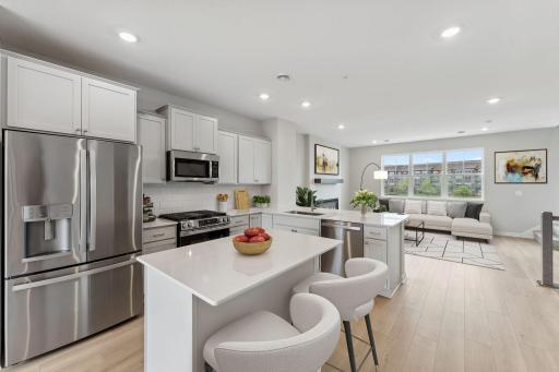 Light and bright! The finishes blend an elevated feel with functionality. The L-shaped kitchen with island and adjacent dining area make a perfect space for both everyday meals and entertaining. Photo of similar home, color and finish will vary.