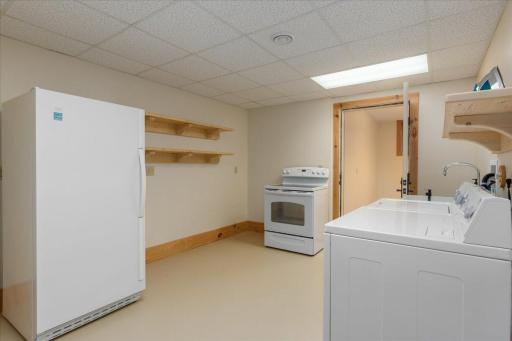 This is a working kitchen space with a second fridge, oven, sink and washer and dryer.
