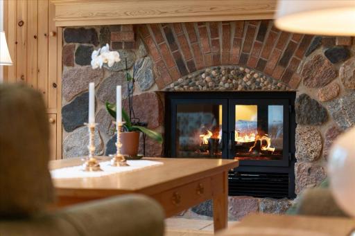 The custom stone wood burning fireplace centers the living room overlooking the lake and connects to the primary suite on the same level.