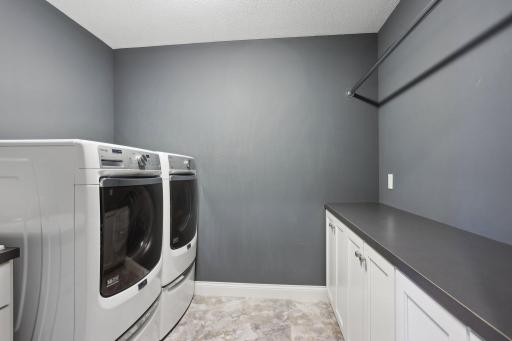 Upper level laundry room features built-in cabinetry and folding space
