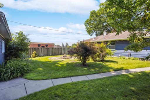 This home has a large backyard with a fire pit and a concrete sidewalk