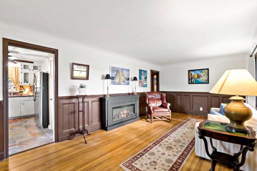 Another view of the light and spacious living room with solid oak floors, an electric fireplace and kitchen with new appliances