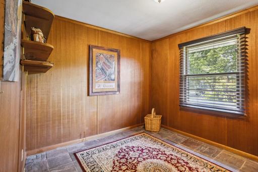 The paneled office/bedroom on the main level with a slate tile floor