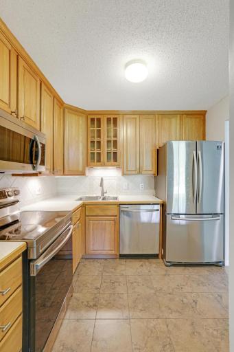Check out this kitchen! Remodeled kitchen with upgraded cabinetry, with glass front cabinet above the sink and ceramic floor tiling.