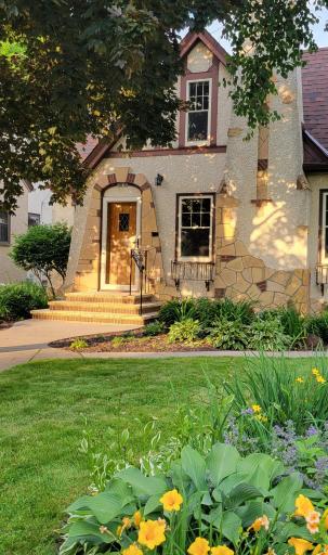 The front entry has been rebuilt with classic cut limestone stairs and newer concrete walkways.