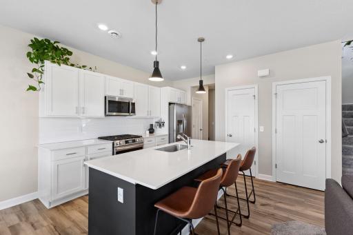 Spacious and bright kitchen with large center island, quartz countertops, a ceramic tile backsplash, white soft-close cabinetry.