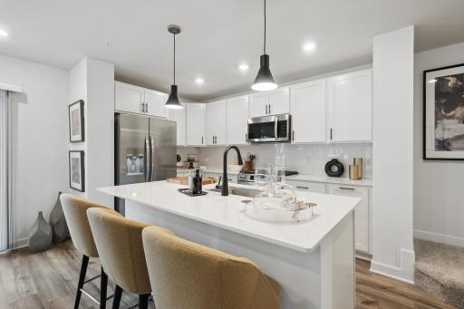 (Photo of decorated model, actual home's finishes vary) Enjoy plenty of seating at the kitchen island and dining area adjacent to the kitchen. Perfect for entertaining or having a family meal together.