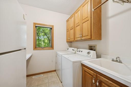The main floor laundry features a built-in utility sink, with cabinetry and shelving designed to keep cleaning supplies organized & provide a convenient space for hanging delicates. An additional refrigerator is included for beverages & extra food.
