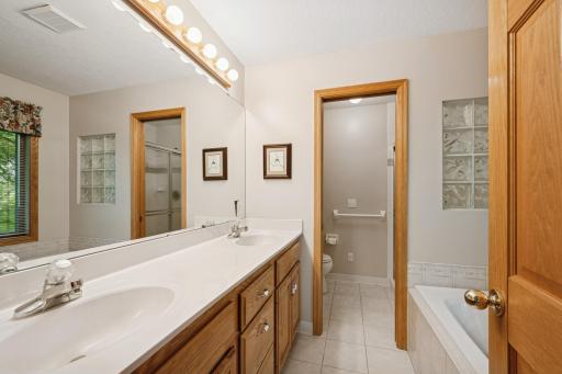 Owner's private bath is complete with jetted tub, tile floors, glass block shower accent, a separate shower and dual sinks. A pocket door offers privacy.