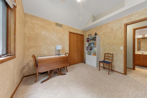 This bedroom stands out with a striking curved window, a high ceiling, and a built-in display shelf.