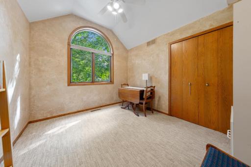 This bedroom stands out with a striking curved window, a high ceiling, and a built-in display shelf.