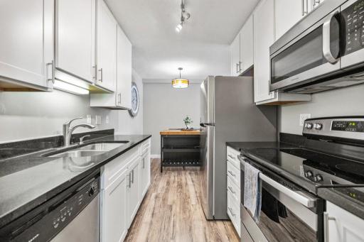 Sleek, modern, and move-in ready — this updated galley kitchen features stainless steel appliances, crisp white cabinetry, and beautiful wood-look flooring that flows into a cozy dining nook. Perfect blend of style and function!