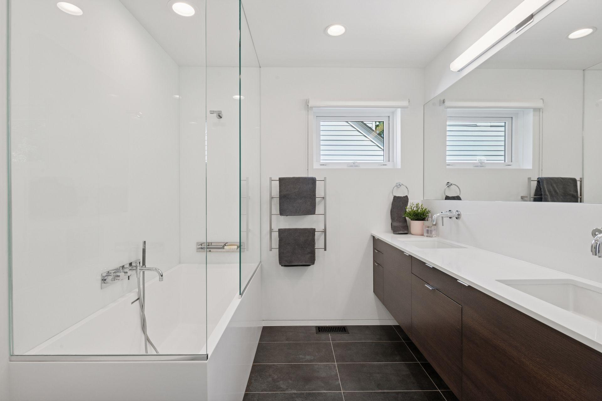 Primary bathroom suite with new double sink, new tub, new tile, new countertops, lighting, and full width mirror