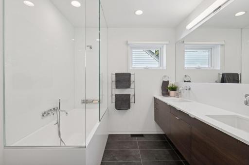Primary bathroom suite with new double sink, new tub, new tile, new countertops, lighting, and full width mirror
