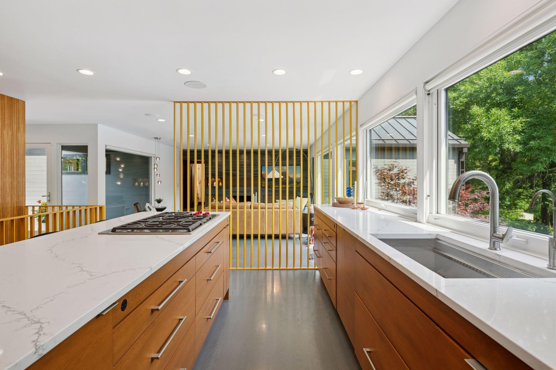 Newly updated kitchen with custom cabinetry, new sink, new quartz countertops, new faucet, ice maker, and mid-century modern room divider