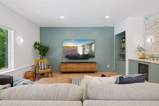 New lower level family room with custom slat wall, storage / display cabinet, and full wet bar