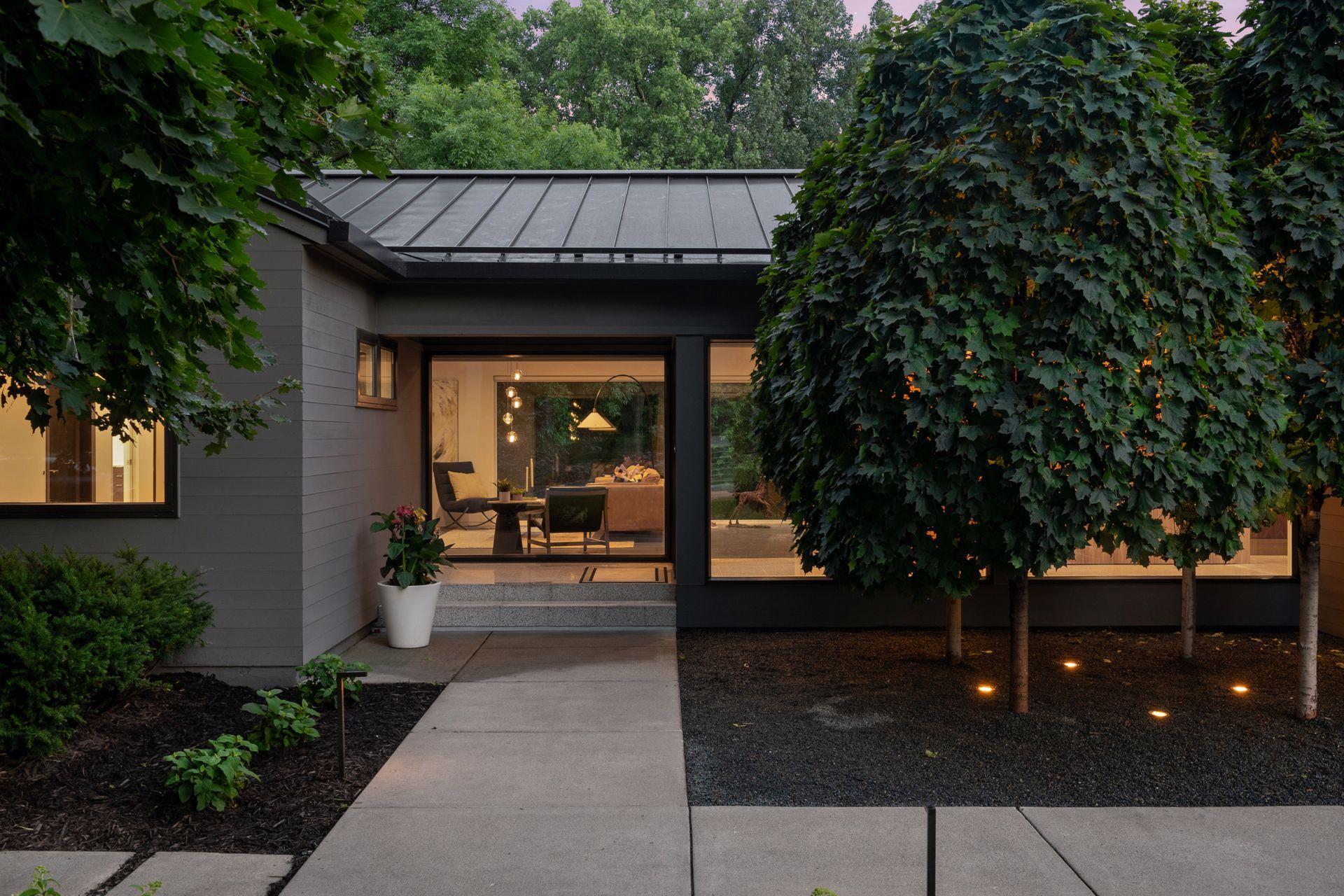 Covered entryway with large glass, landscape lighting, metal roof, and see thru windows