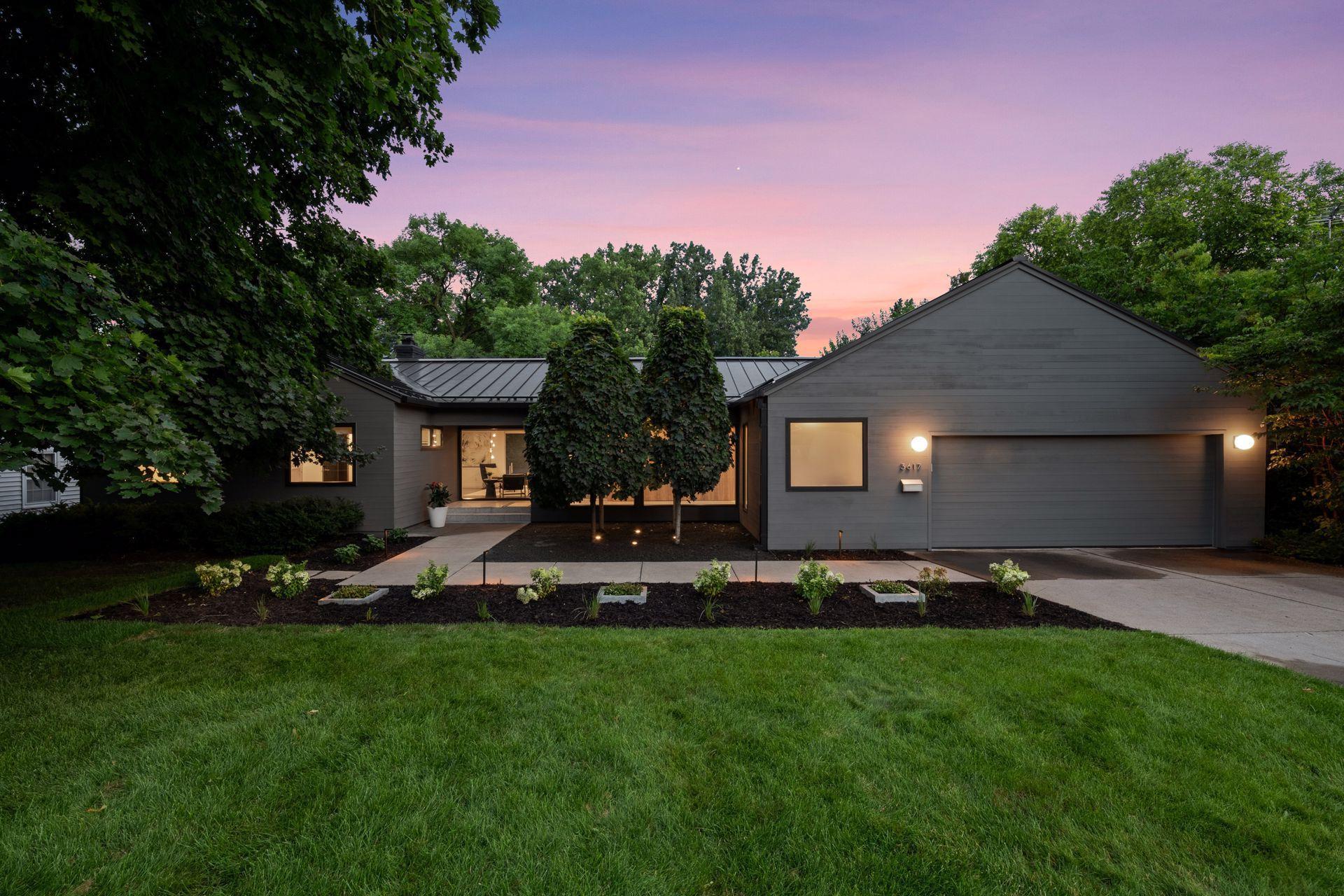 Dusk setting over this mid-century modern rambler with a standing seam metal roof & stunning landscaping