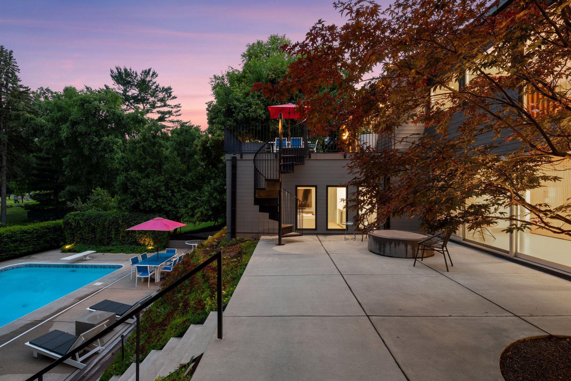 Patio with fire-pit, large sliding doors to walkout basement, stairs to pool, and spiral staircase to upper level deck