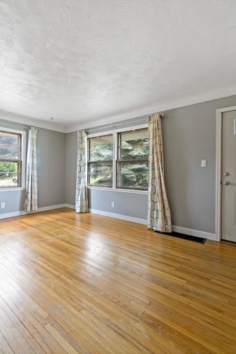 Front Living room boasts bright light through multiple windows and original hardwood floors.