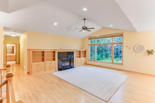 Inviting living room with a cozy gas fireplace, rich natural woodwork, vaulted ceiling, and custom built-in shelving for style and function.
