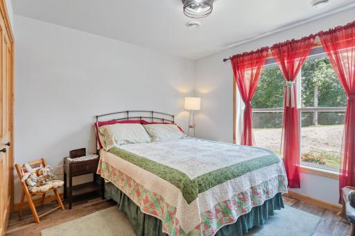 The first bedroom features neutral colors, LVP flooring, and a large window with picturesque views.