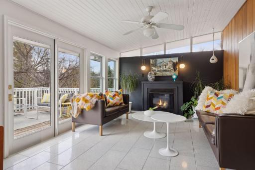 Sunroom with access to the deck leading down to the pool. Includes gas fireplace and heated Terrazzo floors