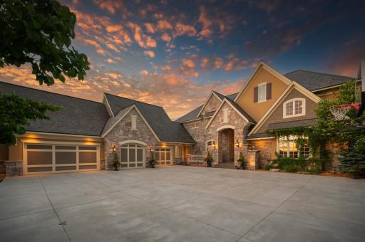 A grand and welcoming front entrance with stately stonework, custom architectural elements, a slate roof, and lush landscapingâsetting the tone for the luxury that awaits inside.