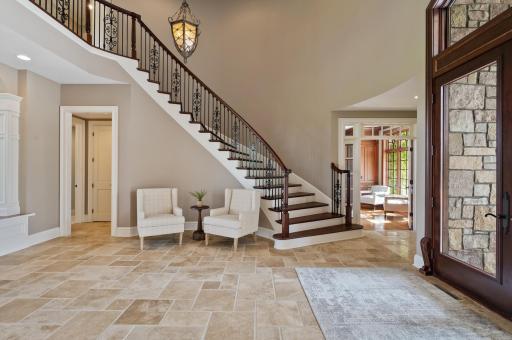 The elegant curved staircase with its ornate iron balusters is a stunning focal point of the grand foyer.