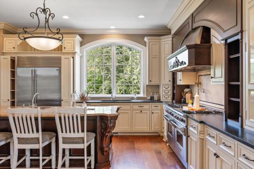 The spacious kitchen island, the abundance of natural light from the arched window, and the integrated Sub-Zero refrigerator are highlights of this culinary space.