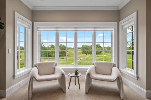 The primary suite sitting area offers an immersive view of the golf course.