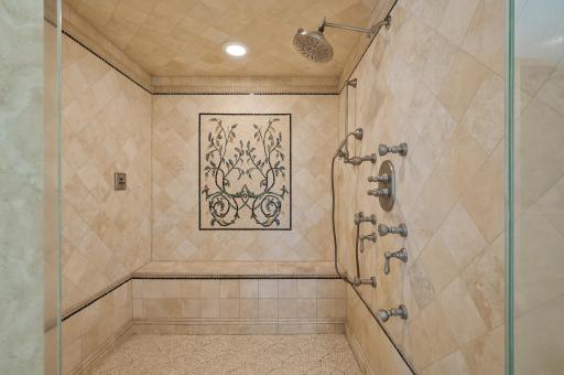 Luxurious walk-in shower with multiple shower heads and a built-in bench.
