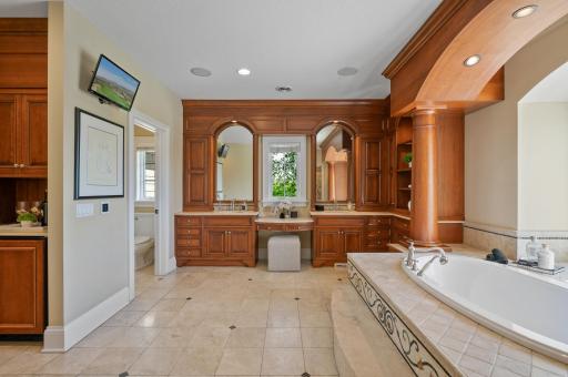 Enjoy the convenience of dual vanities and a dedicated makeup station in this expansive and luxurious bathroom.