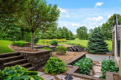 Tiered gardens and charming stone pathways enhance the beauty of the backyard landscape.