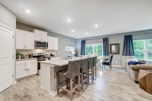 Bright open kitchen with quartz countertops and stainless steel appliances. Model picture shown. Colors and finishes may vary.