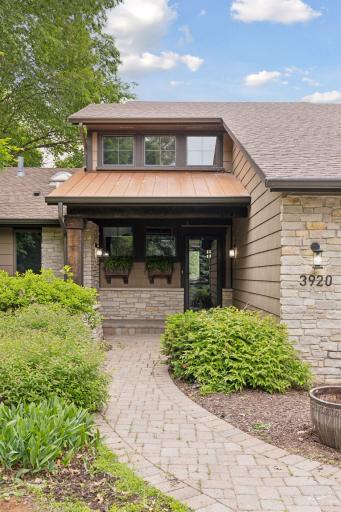 Beautiful covered entry with copper metal roofing and paver path greet you