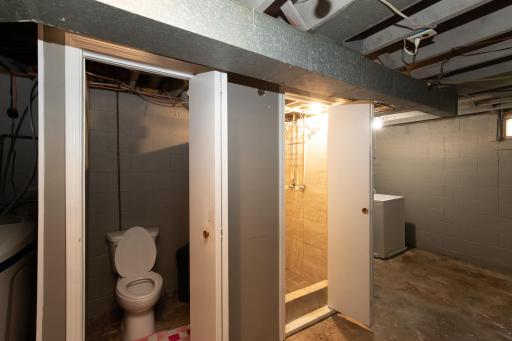 The lower level bathroom consists of a toilet, a shower and a nearby laundry sink, all in the utility room