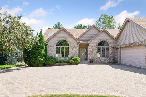 Front of Home with beautiful paver driveway and floor to ceiling windows.