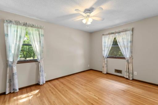 Two additional bedrooms feature durable wood flooring, ceiling fans, and plenty of closet space.