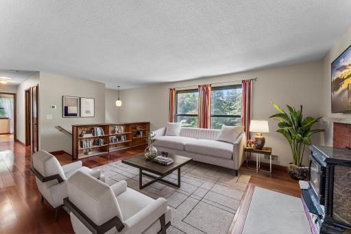Inside, you’re welcomed by a bright and airy upper-level living room where rich wood floors, large windows, custom book shelves, and a charming wood-burning stove with tile and brick detailing create a warm, inviting atmosphere.