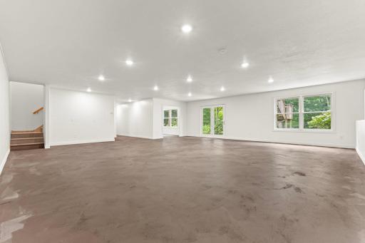 Spacious newly finished basement with sheetrock walls, trim, ceiling, updated lighting, and painted floors.