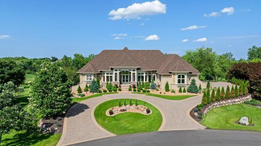 This home makes a striking first impression with its circular paver driveway, pristine landscaping, and grand architectural presence.