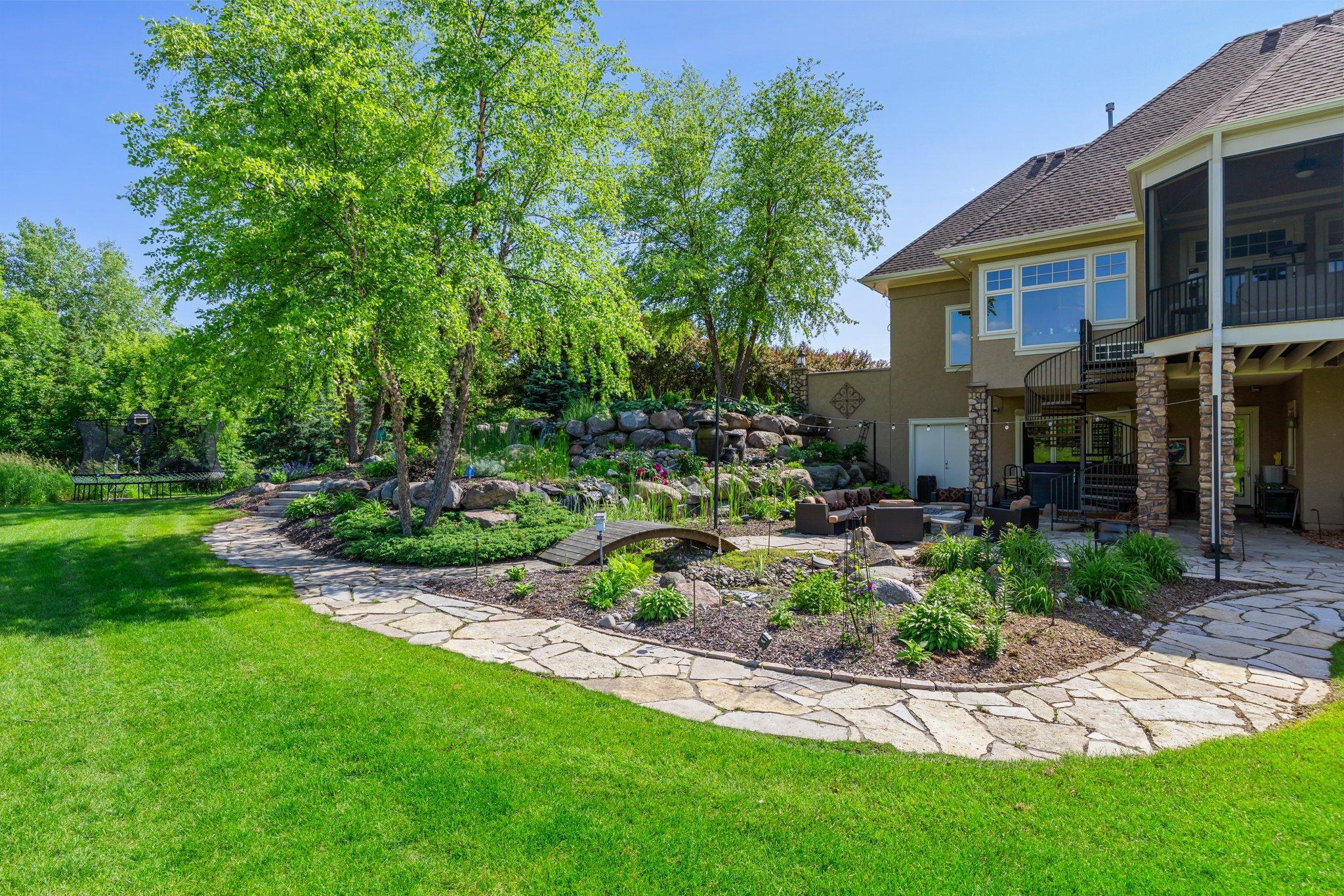 Professionally landscaped backyard with stone paths, water feature and terraced gardens. Multiple seating areas and a screened porch offer plenty of space to relax or entertain in a private, natural setting.