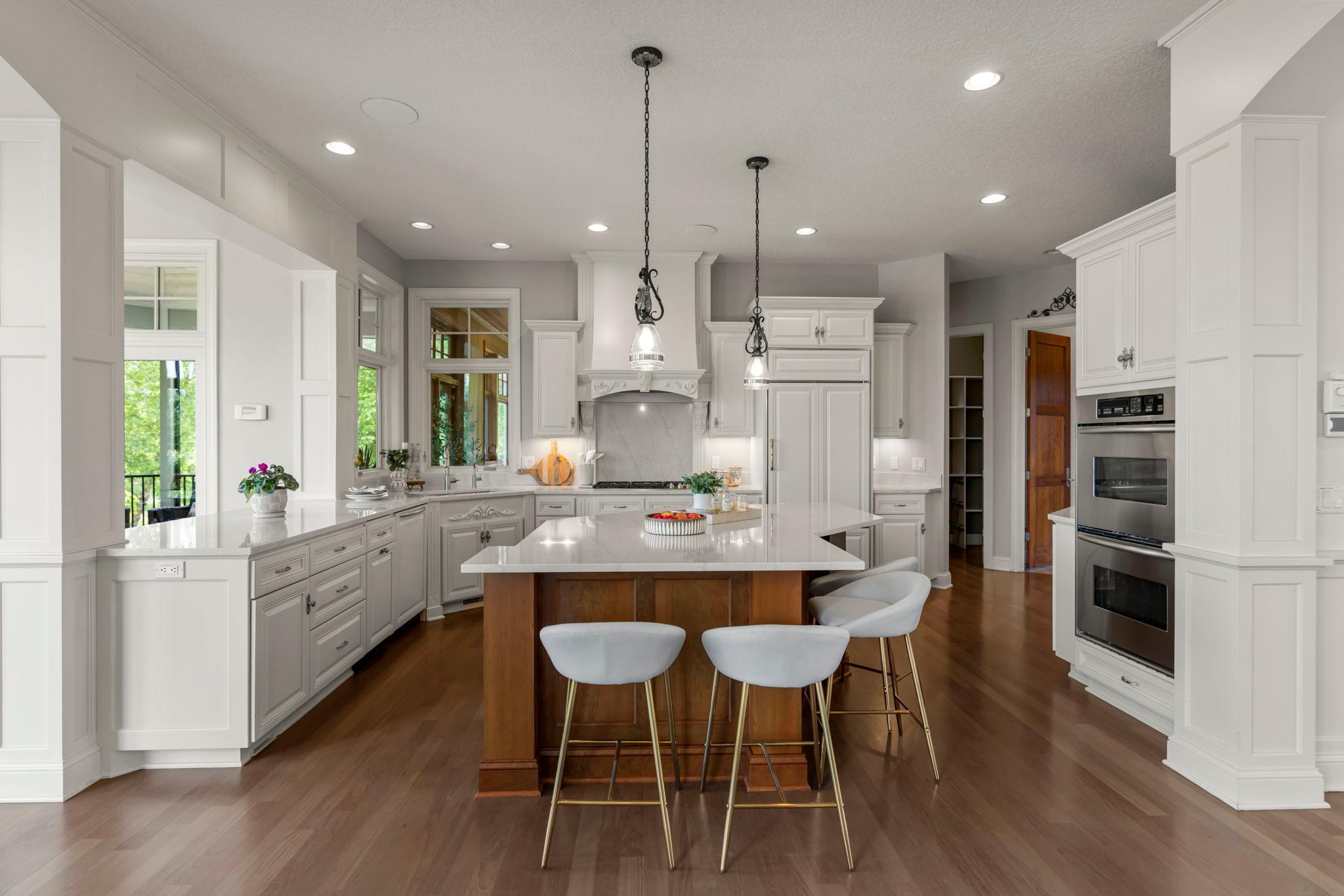 Gourmet kitchen featuring a large center island, double ovens, built-in refrigerator and custom cabinetry with ample storage. Designed for entertaining and everyday living, with rich wood floors and open sightlines to adjoining living spaces.